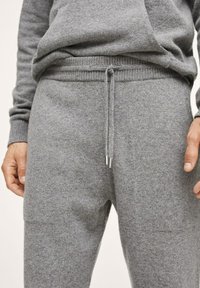 Grijze sweatpants gemaakt van zachte stof, met een trekkoord in de taille met metalen uiteinden, geribbelde boorden en zijzakken.