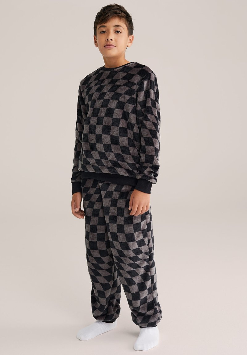 Conjunto de loungewear de polar a cuadros en negro y gris, con mangas largas y puños elásticos. Los pantalones tienen una cintura elástica y un corte relajado.