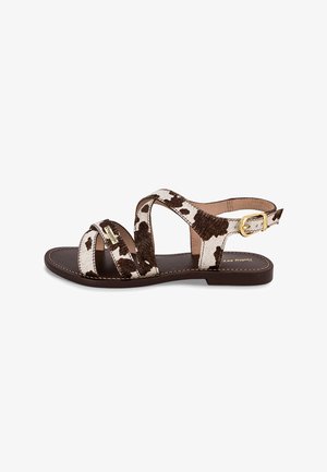 Sandali con stampa maculata marrone e bianca con design a incrocio, dotati di chiusura con fibbia e suola piatta marrone. Parte superiore strutturata e dettagli cuciti.