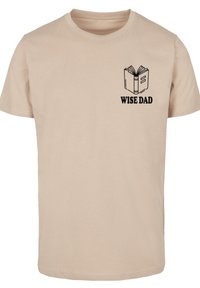 Beige cotton t-shirt featuring a black graphic of an open book and the text "WISE DAD" above it. Short sleeves and standard fit.