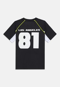 Svart kortermet jersey med hvit nummer "81" og teksten "LOS ANGELES", med gule detaljer på skuldersømmene og hvite sidestykker.