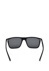 Lunettes de soleil rectangulaires noires avec des verres foncés et des branches légèrement courbées sur fond blanc.