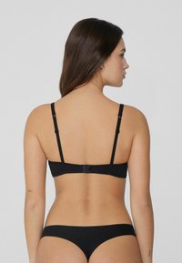 Zwart ondergoedset met een bralette met verstelbare bandjes en een haaksluiting, gecombineerd met bijpassende bikinistijl onderbroeken. Zachte textuur.
