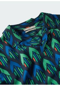 Lyhythihainen paita laivastonsinisellä pohjalla ja vihreän, sinisen ja oranssin geometrisella kuviolla. Paidassa on kaulukset ja mustat napit. Normaali istuvuus.