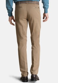 Beige chino's met een rechte pasvorm, gemaakt van zacht katoen, met achterzakken met knopen en een bruine tailleband. Draagt met donkere schoenen.