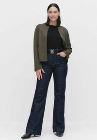 Olivgrön strukturerad jacka, svart topp, högmidjade mörk denimjeans, bältesspänne i form av en guld fjäril, svarta skor, långa ärmar.