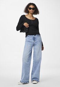 Black ribbed long-sleeve top with buttons, light blue wide-leg jeans, black sunglasses, and a black handbag. Casual outfit with contrasting tones.