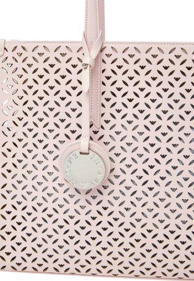 Borsa tote perforata rosa con un design geometrico, texture liscia, due manici e un'etichetta circolare con logo in rilievo.