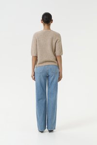 Maglione beige a maglia con maniche a palloncino corte e jeans a gamba larga blu chiaro con tasche posteriori, mostrato di spalle su uno sfondo neutro.