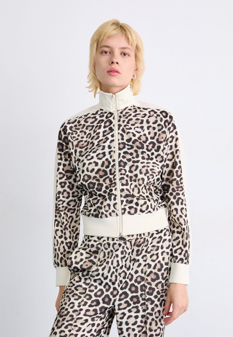 Leopard print zip-up jacket with high collar, fitted cuffs, and matching pants. Made of smooth fabric with a soft texture. Accented with cream details.