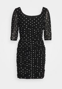 Musta istuva mekko, jossa on pilkkuja, rypytetty kangas ja läpinäkyvät puffihihat. Neliökaula-aukko ja takasaumavetoketju.