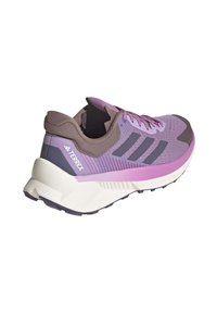 Fialové a šedé trailové běžecké boty Adidas Terrex s bílou podrážkou a černou podešví, viděné z boku a zezadu.