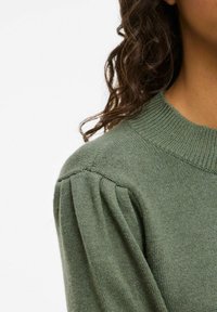 Groene gebreide trui met een geribde ronde hals en geplooide schouderdetails, gemaakt van een zachte, gestructureerde stof.