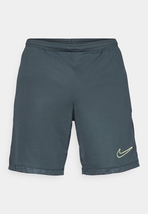 Szürke sportos rövidnadrág, gumis derékkal, hálós textúrával az alján, és sárga, fényvisszaverő Nike logóval az oldalon.