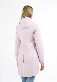 Giacca impermeabile rosa con cappuccio, polsini elasticizzati e vita con cintura. Pley sottostante nascosto per una maggiore libertà di movimento. Texture morbida e liscia.