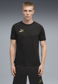 Sort atletisk t-shirt med korte ærmer, prydet med guld "KING" tekst og logo på brystet. Glat stof og rund hals.