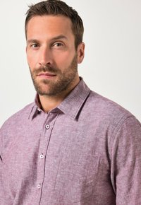 Camisa de manga corta color púrpura claro con botones, tejido texturizado, bolsillo único en el pecho y botones de contraste.