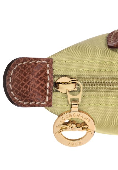 Green nylon pouch with brown leather accents, featuring a gold zipper and a circular logo tag inscribed with "LONGCHAMP 1948."