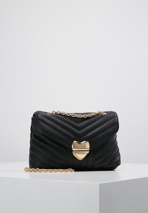 Schwarze, gesteppte Handtasche mit Zickzackmuster, goldener Kette und herzförmigem Verschluss. Aus synthetischem Material mit glatter Textur gefertigt.