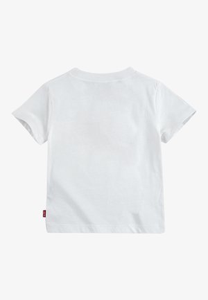 Bijela pamučna majica kratkih rukava s okruglim izrezom. Ima malu crvenu oznaku na donjoj lijevoj strani. Glatka tekstura, jednostavan dizajn.