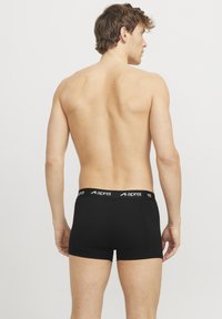 Schwarze Boxershorts aus glattem Stoff, mit einem elastischen Bund mit Logo und einer enganliegenden Passform, speziell für Komfort und Flexibilität entworfen.