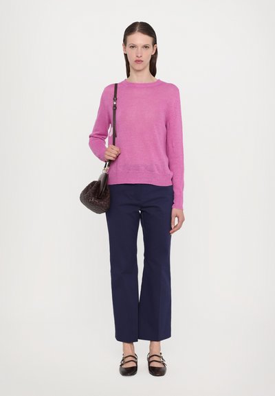 Maglione lavorato a maglia fucsia, pantaloni blu navy a gamba larga, borsa scura con texture e scarpe marroni con fibbie. Design semplice e moderno con una forma aderente.
