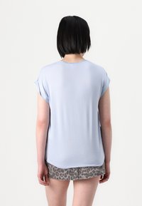 Top azzurro chiaro a maniche corte con scollatura rotonda e una texture liscia, abbinato a una gonna in denim grigia con stampa leopardata.