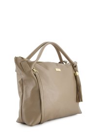 Beige leren handtas met een gestructureerd oppervlak, dubbele handvatten, een goudkleurige logo plaat en een decoratieve kwastaccent aan de zijkant.