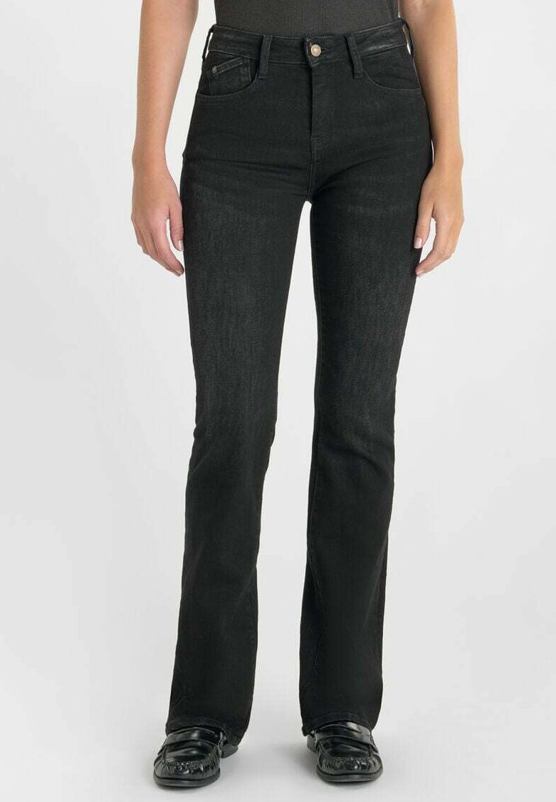 Zwarte flared jeans van denim, met een hoge taille, vijf zakken en subtiele textuur. Het model draagt zwarte schoenen met details.