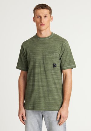 Camiseta de rayas verdes con cuello redondo, mangas cortas y un bolsillo frontal con una etiqueta de logo negra. Tejido suave y texturizado.