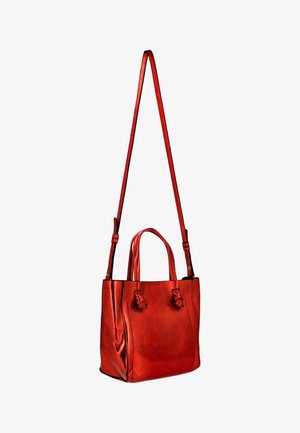 Piros bőrtáska két rövid fogóval és egy hosszú, állítható vállpánttal, elülső oldalain díszítő csomókkal.