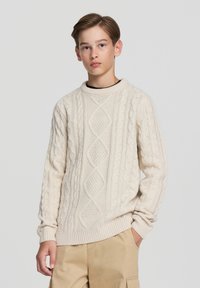 Maglione lavorato a maglia color crema con design a trecce e motivi a diamante, scollo rotondo e polsini e orlo a coste.