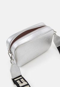 Borsa in pelle textured argentata con due scomparti con zip e una tracolla rimovibile con un motivo in bianco e nero. Design compatto e rettangolare.