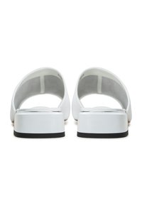 Sandali bianchi dal design elegante, con schienale aperto, materiale morbido e una suola nera a contrasto. Stile minimalista senza hardware visibile.