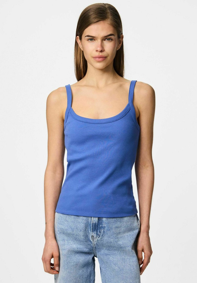 Camiseta de tirantes anchos de color azul con canalé y escote redondeado, combinada con jeans de color azul claro. La tela parece suave y elástica.