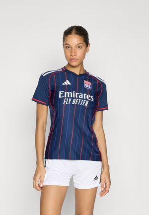 Blauwe voetbalshirt met rode verticale strepen, wit logo en tekst, korte mouwen, gecombineerd met witte shorts. Ontworpen voor actieve kleding.