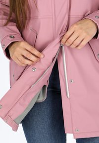 Giacca rosa impermeabile con bottoni a pressione, zip argentate e interno foderato. I polsini hanno bottoni a pressione regolabili per una vestibilità perfetta.