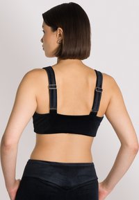 Bralette in corduroy nero con spalline larghe, accessori in argento e finitura testurizzata. Il design presenta una silhouette corta e una forma aderente.