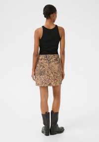 Top negru cu dungi, fustă mini bej cu model leopard și bottine negre. Textură netedă, design ajustat și lungime până la mijlocul coapsei.