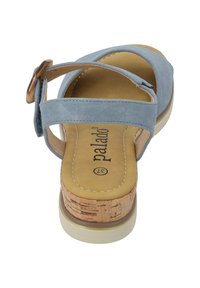 Blue suede sandal with two crossover straps and a buckle, featuring a cork-covered wedge heel and a beige rubber sole.
