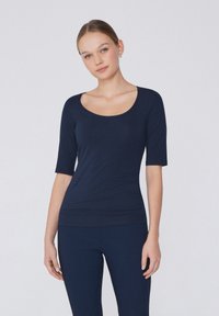 Námořnický modrý přiléhavý top s širokým výstřihem a krátkými rukávy. Vyrobený z měkkého materiálu s hladkou texturou, s bezešvým designem.