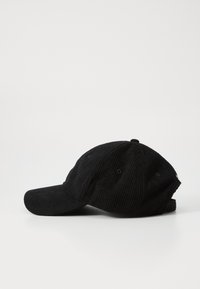 Casquette en velours côtelé noir avec une visière courbée, dotée de six œillets de ventilation et d'une sangle ajustable à l'arrière. Matériau texturé et design classique.