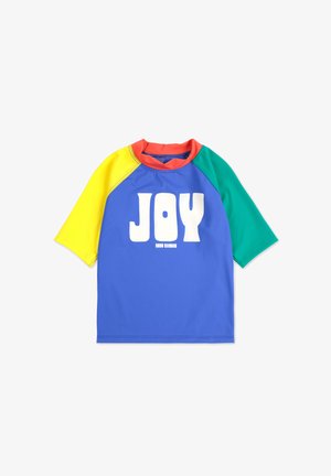 Maglietta a maniche corte multicolore con corpo blu, maniche gialle e verdi, colletto rosso e testo bianco ben visibile che recita "GIOIA". Tessuto morbido.