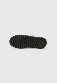 Black rubber shoe sole with a textured pattern, featuring grooves and a prominent triangle design. The edges are slightly rounded.