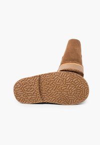 Bottine en daim marron avec un bout arrondi, des coutures beiges et une semelle en caoutchouc texturée dotée d'un design de grip à motifs.