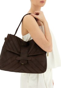 Borsa a tracolla in pelle marrone con un motivo a strisce testurizzate, grande chiusura a calamita e cuciture a contrasto. Presenta una tracolla.
