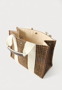 Καφέ καρό τσάντα με φαρδιές κρεμ καμβάδες λαβές, κλείσιμο με κουμπί και μπεζ εσωτερική επένδυση, εμφανίζεται ελαφρώς ανοιχτή σε λευκό φόντο.