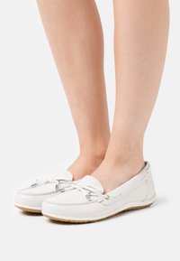 Zapatos de cuero blanco estilo mocasín con punta redonda, detalles de cordones y una suela texturizada. Exterior suave con sutiles acentos de costura.