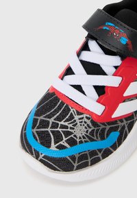 Scarpa sportiva nera con accenti rossi e blu, caratterizzata da un motivo a ragnatela sulla punta, lacci bianchi e una cinghia nera con una grafica di Spiderman.