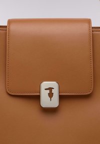 Borsa in pelle color tan con chiusura a ribalta piatta, dotata di una fibbia in metallo argentato con un design a taglio. Texture liscia con cuciture pulite.